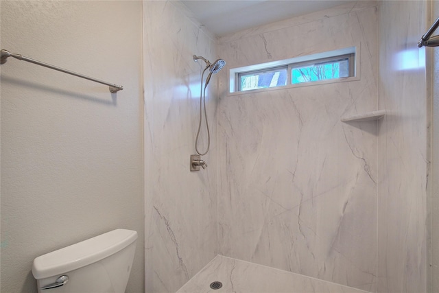 bathroom with a marble finish shower and toilet