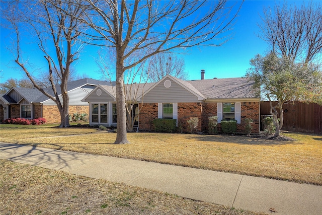 ranch-style house featuring brick siding, a front yard, and fence