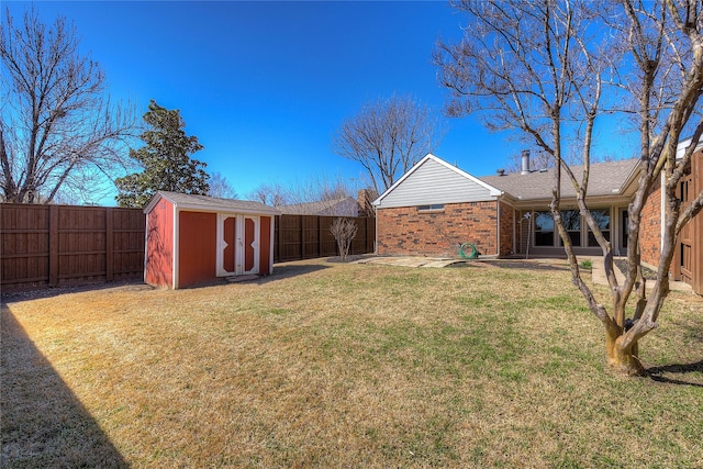 view of yard featuring an outbuilding, a fenced backyard, and a shed