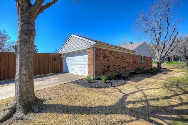 view of home's exterior with concrete driveway, an attached garage, fence, and brick siding