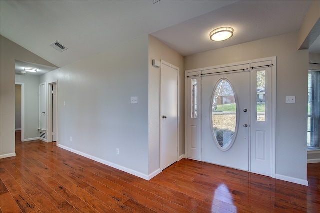 foyer with baseboards, wood-type flooring, lofted ceiling, and visible vents