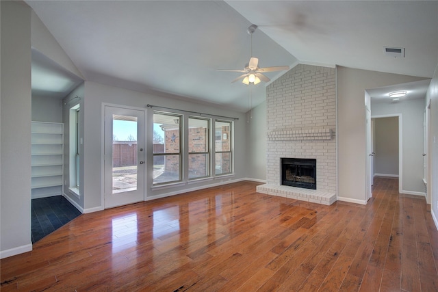 unfurnished living room featuring visible vents, hardwood / wood-style flooring, a brick fireplace, ceiling fan, and vaulted ceiling