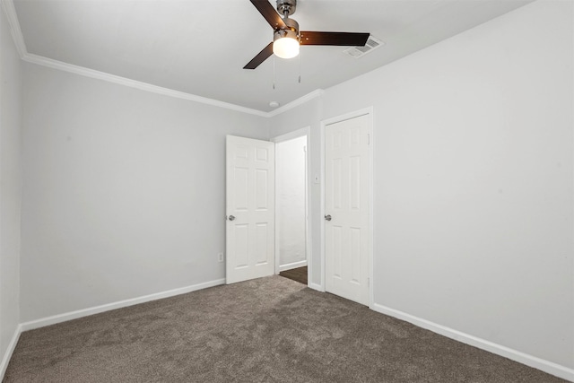 carpeted spare room featuring ceiling fan, visible vents, baseboards, and ornamental molding