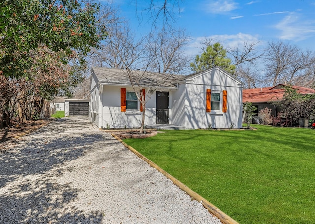 view of front of home with a front yard, an outbuilding, a detached garage, and stucco siding