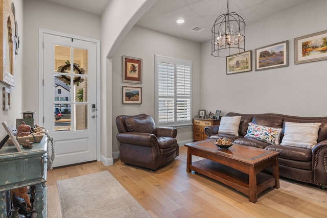 living room with baseboards, light wood-type flooring, recessed lighting, arched walkways, and a notable chandelier