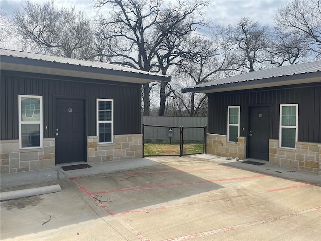 exterior space featuring board and batten siding, stone siding, and metal roof