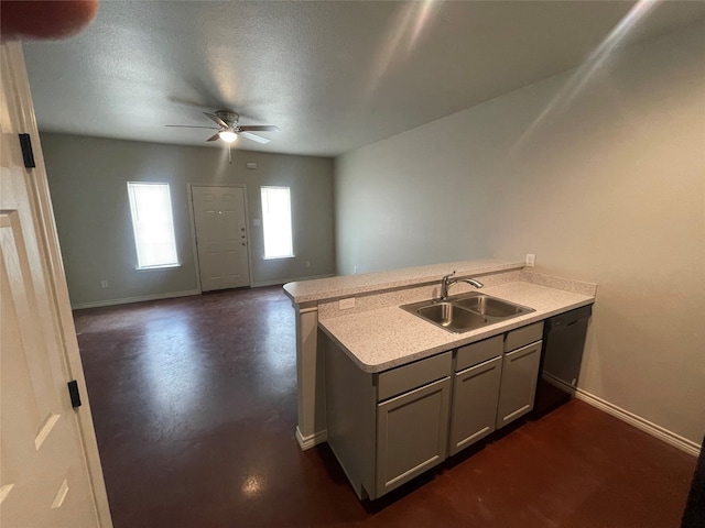 kitchen with a peninsula, ceiling fan, a sink, light countertops, and black dishwasher