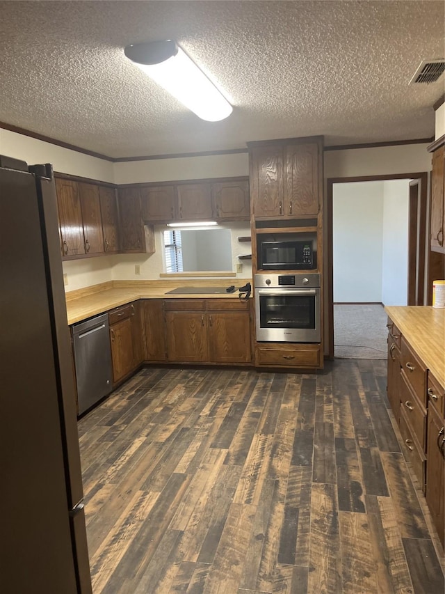 kitchen featuring visible vents, black appliances, dark wood finished floors, light countertops, and a textured ceiling