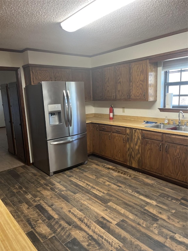 kitchen with dark wood-style flooring, a sink, light countertops, dark brown cabinets, and stainless steel refrigerator with ice dispenser