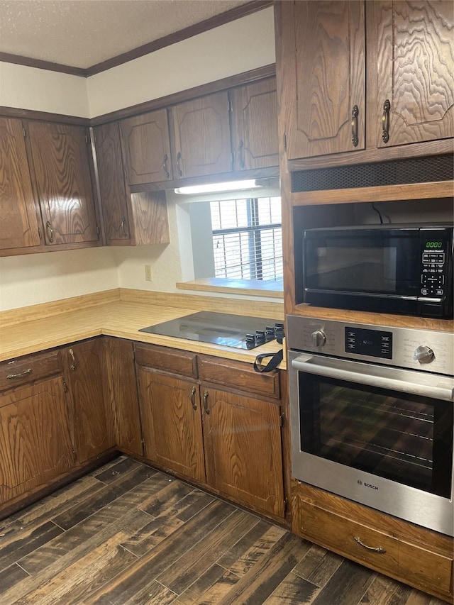 kitchen with a textured ceiling, dark wood-type flooring, black appliances, and light countertops