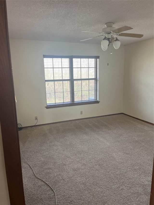 carpeted spare room featuring a textured ceiling and baseboards