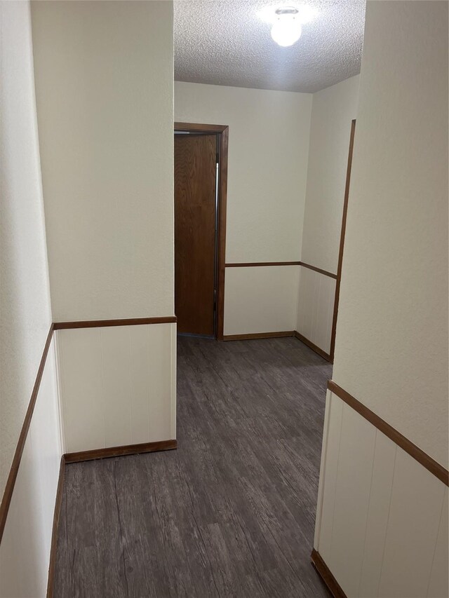 spare room with wainscoting, a textured ceiling, and wood finished floors