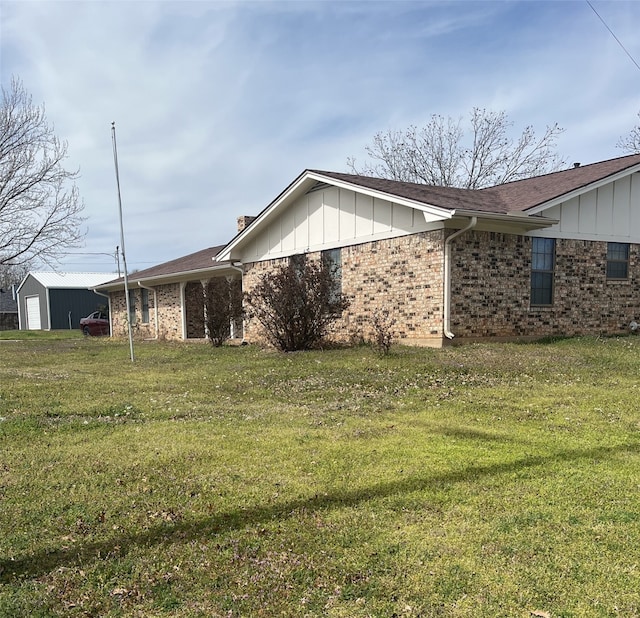 view of side of property featuring a yard, a garage, board and batten siding, and brick siding