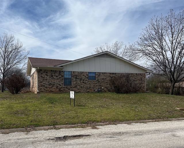 view of property exterior featuring brick siding, a lawn, and roof with shingles