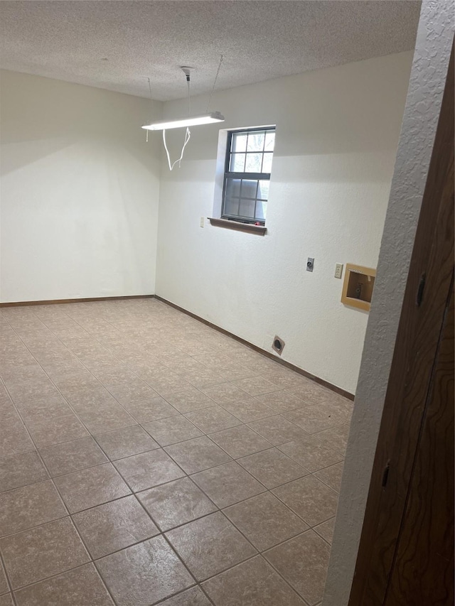 unfurnished room featuring a textured ceiling and baseboards