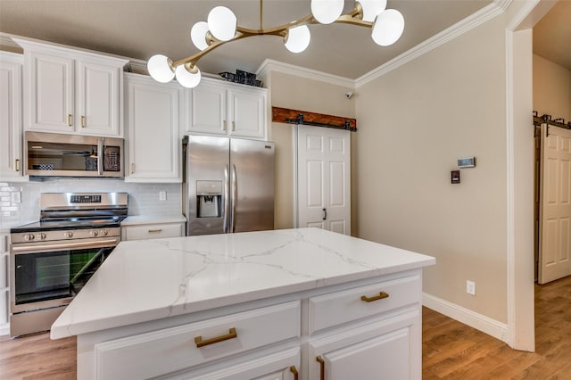 kitchen featuring a barn door, tasteful backsplash, appliances with stainless steel finishes, and ornamental molding