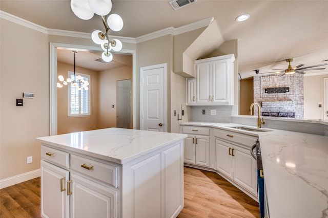 kitchen with visible vents, ornamental molding, a sink, light wood finished floors, and ceiling fan