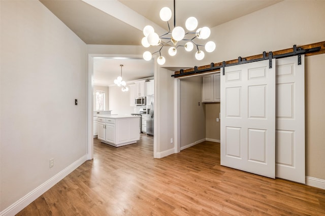 unfurnished dining area featuring a barn door, a notable chandelier, light wood-style floors, and baseboards