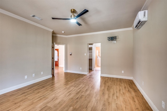 spare room with visible vents, a wall unit AC, light wood-style floors, crown molding, and baseboards