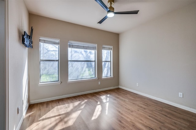 spare room featuring baseboards, wood finished floors, and a ceiling fan