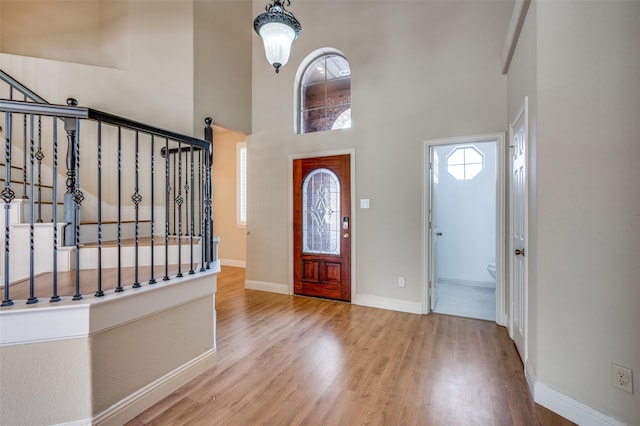 foyer entrance featuring stairway, baseboards, wood finished floors, and a towering ceiling