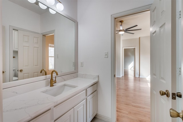 bathroom featuring vanity, wood finished floors, baseboards, ceiling fan, and toilet