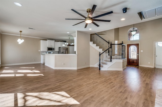 unfurnished living room featuring stairway, baseboards, and light wood-style floors