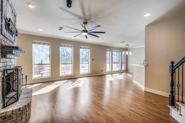 living area with stairs, visible vents, a brick fireplace, and crown molding