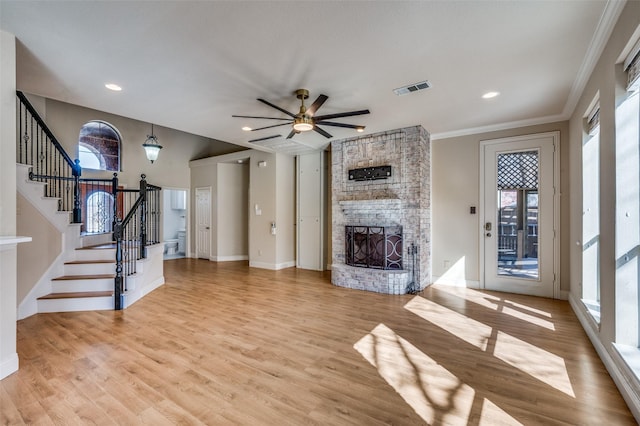 unfurnished living room with light wood-type flooring, visible vents, a fireplace, and stairway