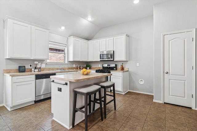 kitchen featuring a breakfast bar area, white cabinets, stainless steel appliances, and light countertops