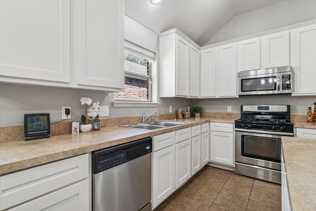 kitchen with dark tile patterned flooring, a sink, light countertops, white cabinets, and appliances with stainless steel finishes