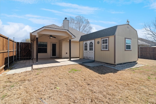 back of property with a ceiling fan, a fenced backyard, a shingled roof, a chimney, and a patio area