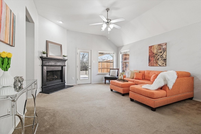 living area featuring baseboards, carpet floors, lofted ceiling, a fireplace with raised hearth, and ceiling fan