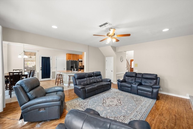 living area with light wood finished floors, visible vents, baseboards, stairs, and a ceiling fan