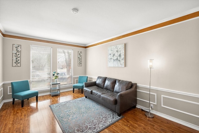 living area featuring a decorative wall, wood finished floors, wainscoting, and ornamental molding