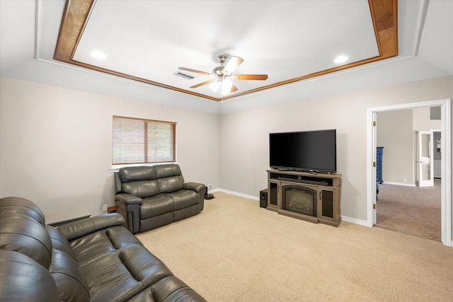 living area featuring a tray ceiling, visible vents, carpet floors, and a ceiling fan