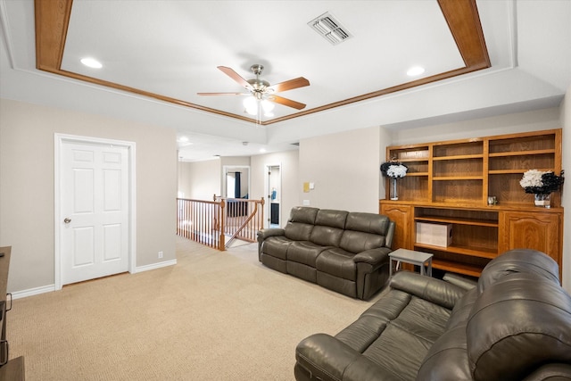 living room with light colored carpet, a tray ceiling, a ceiling fan, and visible vents