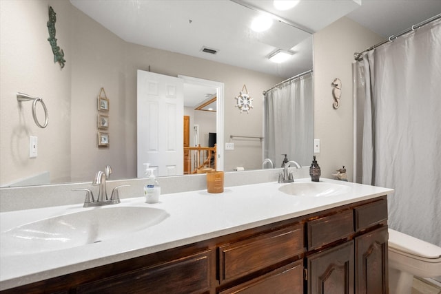 bathroom with a sink, toilet, and double vanity