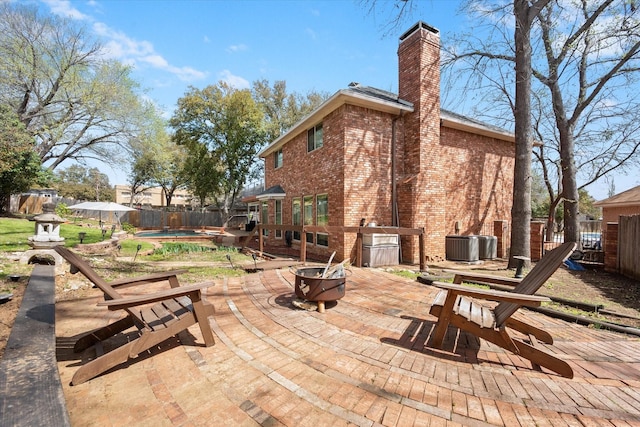 view of patio / terrace with a pool, central AC, a fire pit, and a fenced backyard