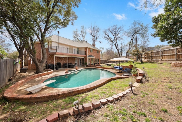 view of pool with a patio area, a fenced backyard, a diving board, and a pool with connected hot tub