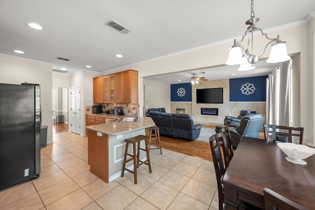 kitchen featuring visible vents, ceiling fan with notable chandelier, a peninsula, freestanding refrigerator, and a sink