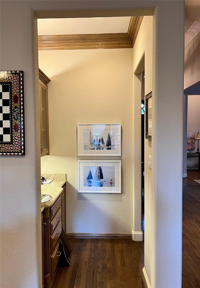 hallway featuring dark wood-style floors, baseboards, and ornamental molding