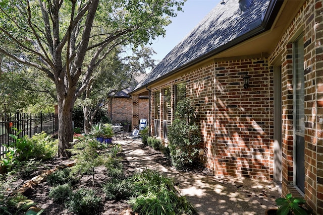 view of side of home featuring a patio, fence, and brick siding