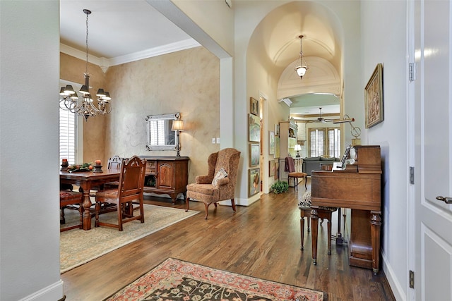 entrance foyer with wood finished floors, baseboards, arched walkways, crown molding, and a notable chandelier