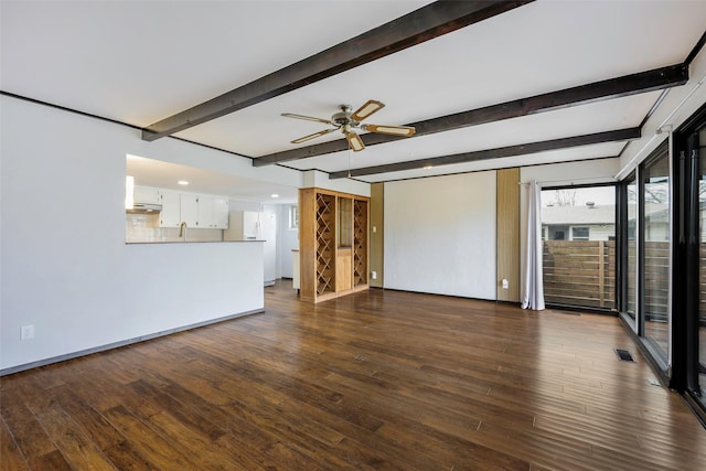 unfurnished living room with visible vents, beamed ceiling, a ceiling fan, baseboards, and dark wood-style flooring