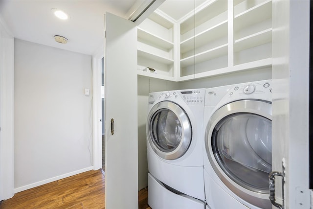 laundry room with laundry area, washing machine and dryer, baseboards, and wood finished floors