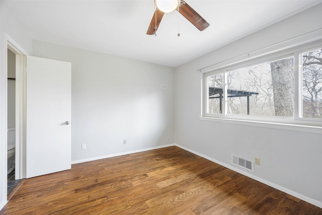 empty room featuring visible vents, a ceiling fan, baseboards, and wood finished floors