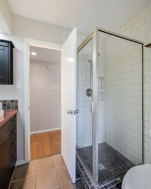 bathroom with tile patterned floors, baseboards, a stall shower, and vanity