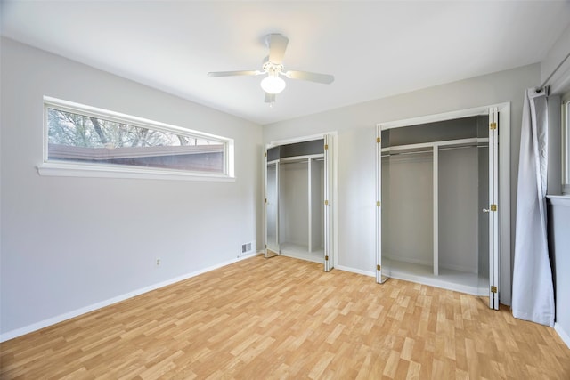 unfurnished bedroom with baseboards, visible vents, light wood finished floors, ceiling fan, and multiple closets