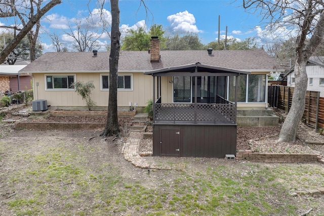 back of house with cooling unit, fence, a sunroom, a shingled roof, and a chimney